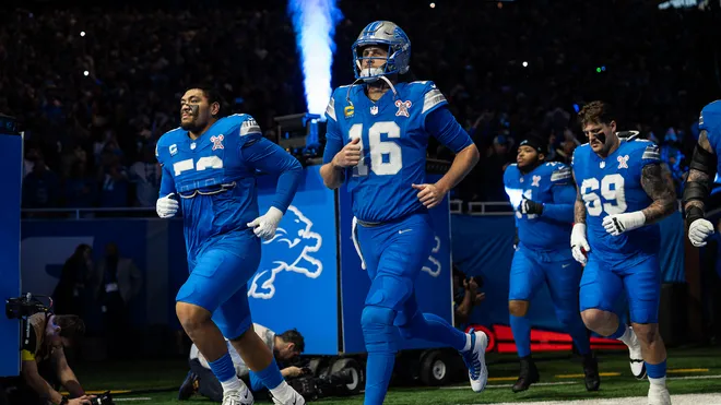 Lions players jogging on field.